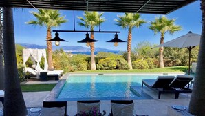 An outdoor pool area with lounge chairs, a table with a vase and glass, and palm trees. - Luxury villa in Cannes with pool and jacuzzi (Cannes)