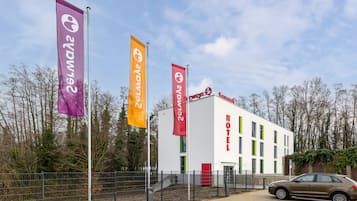 Hotel entrance with a prominent sign and three flags.