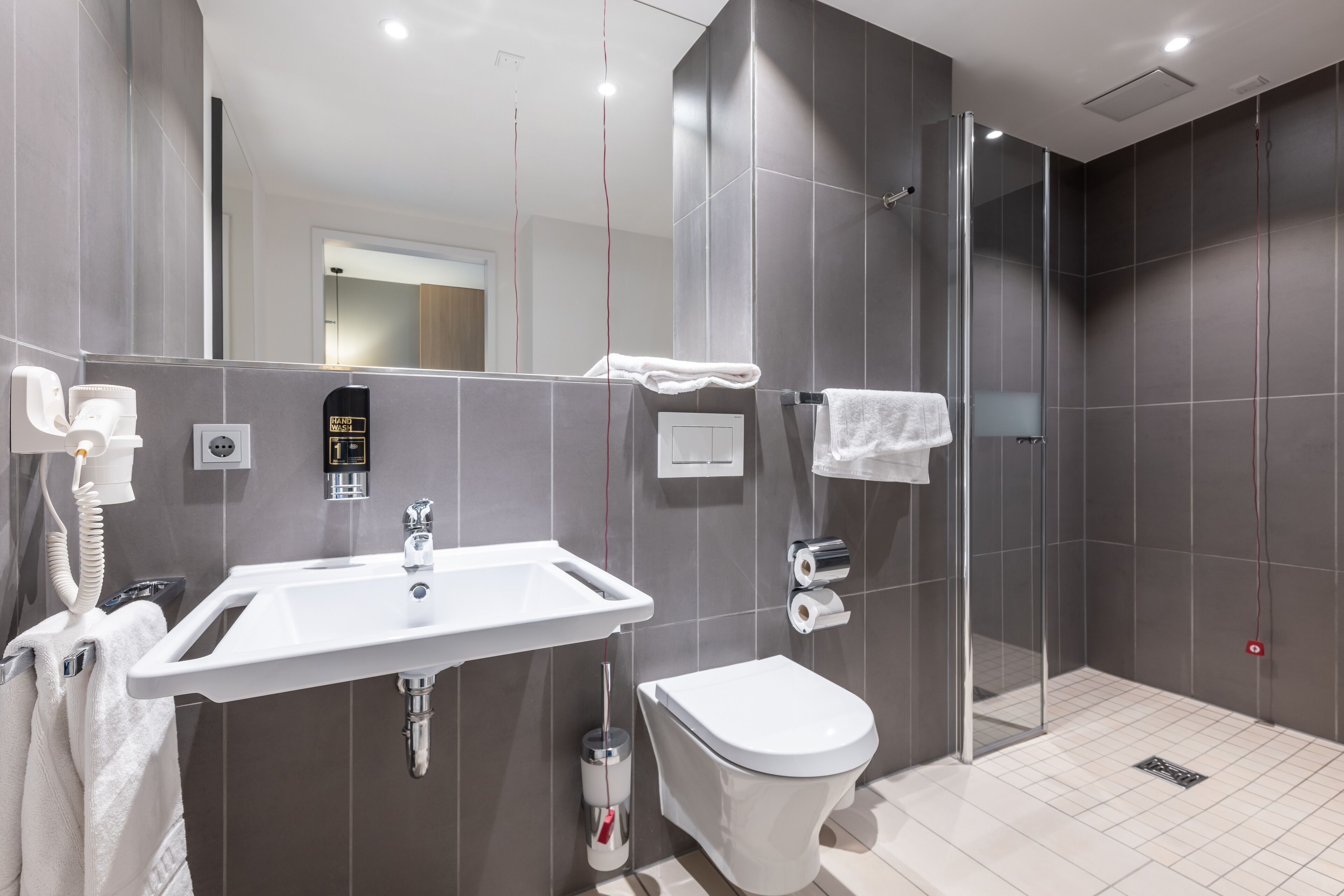 A modern bathroom with a sink, toilet, and glass shower enclosure.