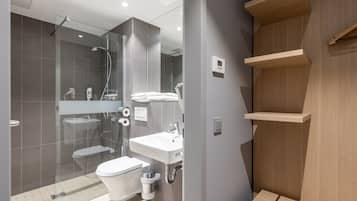 Un baño moderno con ducha de vidrio, un lavabo blanco y un inodoro.