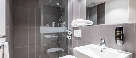 A modern bathroom with a glass-enclosed shower, a white sink, and a toilet.