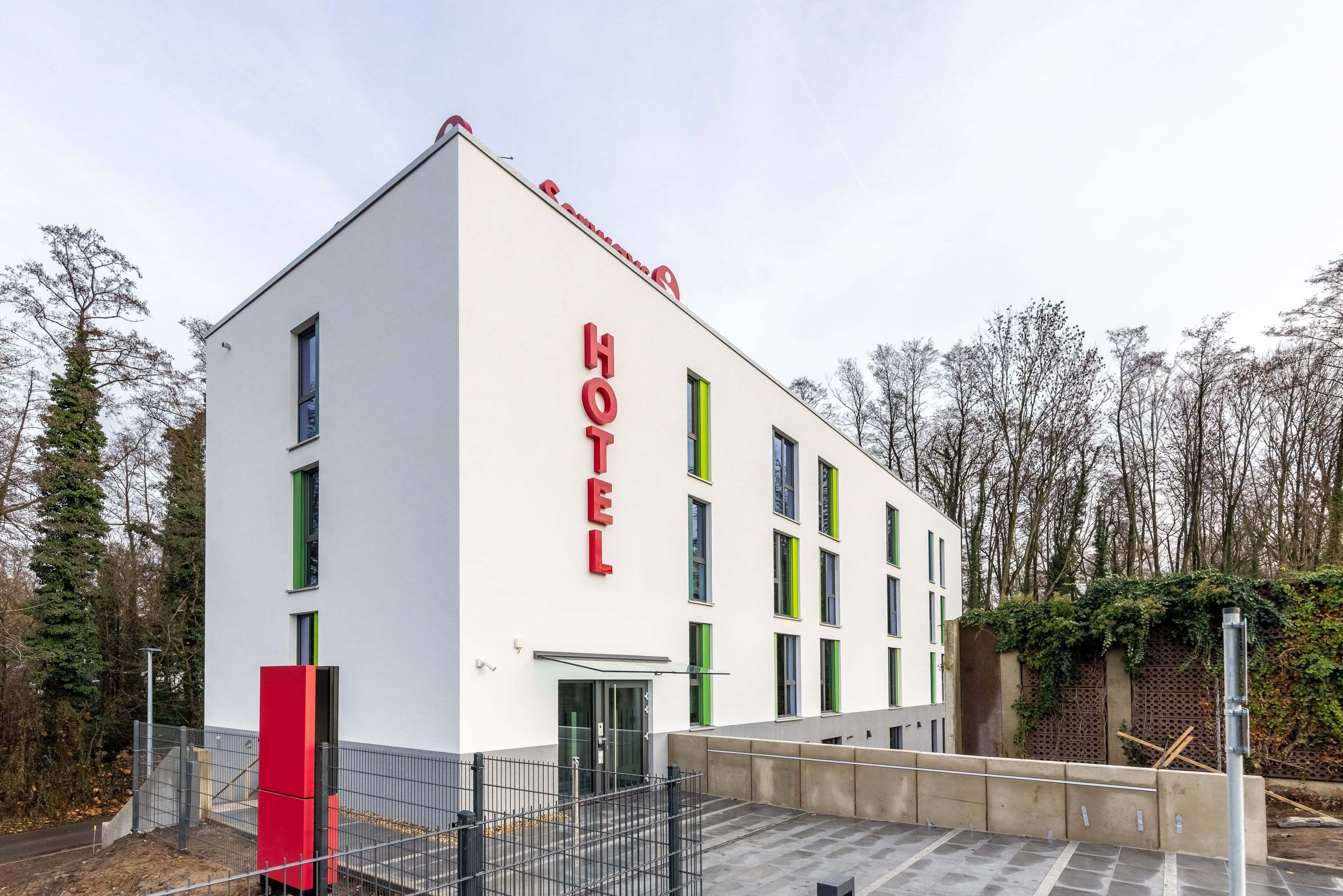 Un hôtel moderne avec une façade blanche et une enseigne rouge.