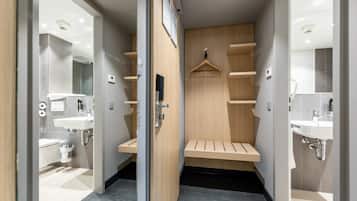A modern bathroom with two sinks, a mirror, and a wooden bench.