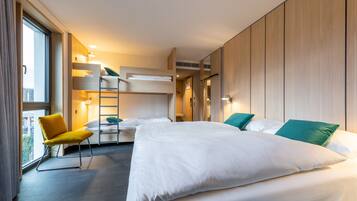 Ein Hotelzimmer mit einem großen Bett, einem gelben Sessel, einer Leiter und Blick ins Freie.
