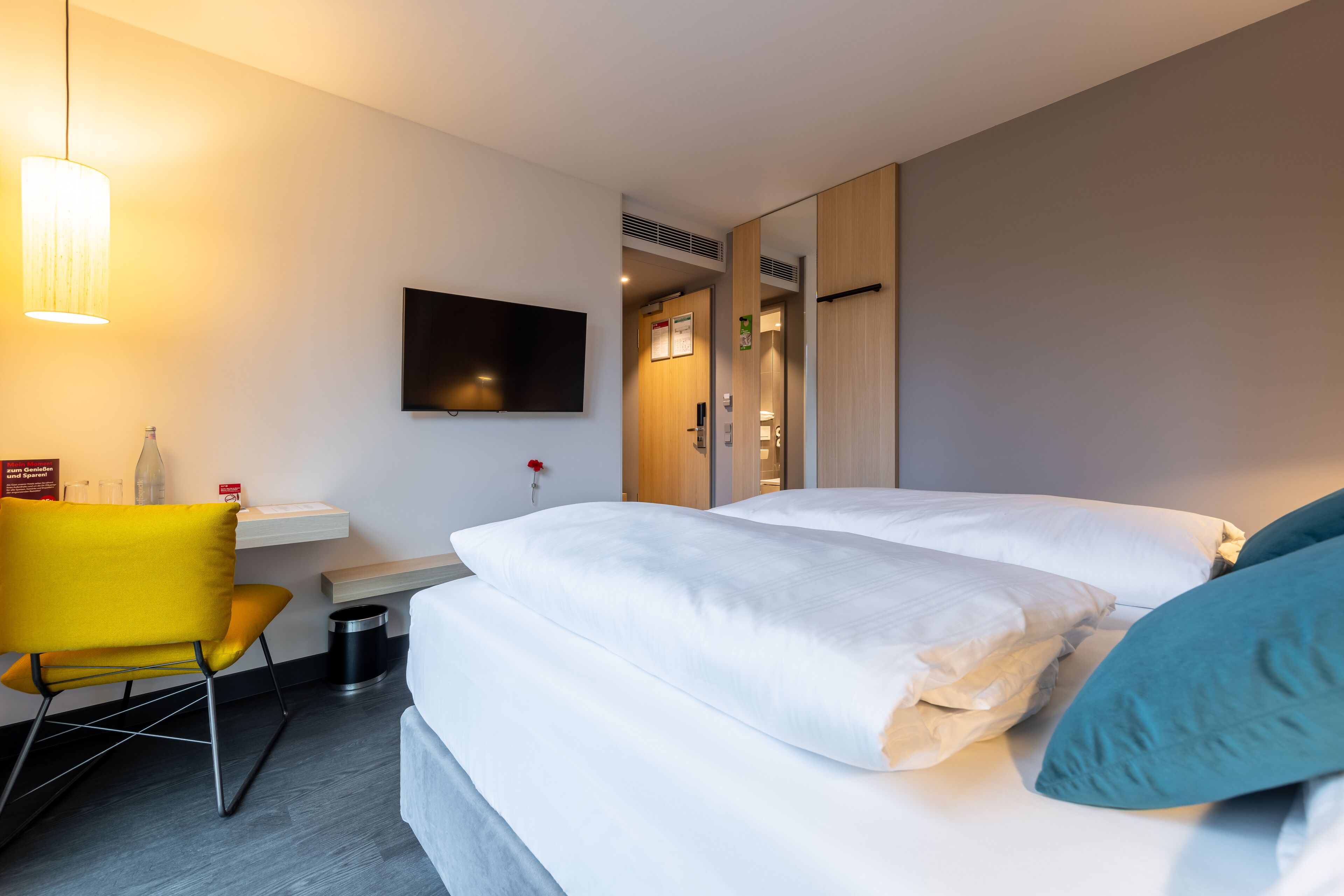Une chambre d’hôtel avec un lit, un bureau, une chaise, une télévision et un miroir.
