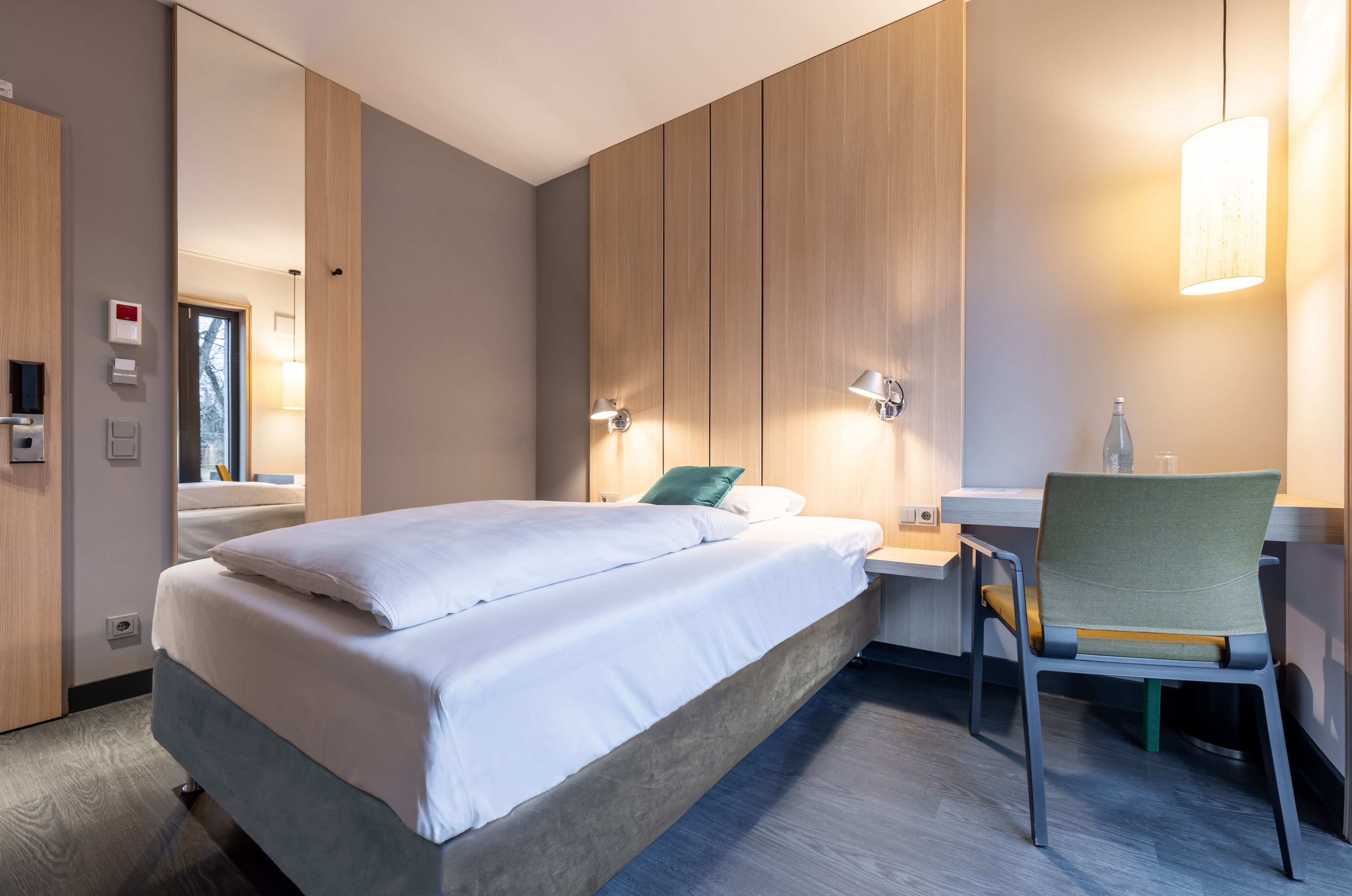 Una habitación de hotel moderna con una cama grande, mesitas de noche, un escritorio y una silla.