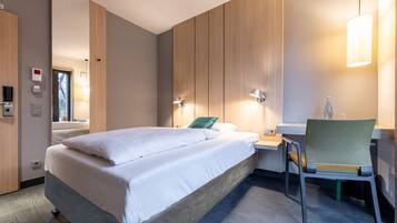 Una habitación de hotel moderna con una cama grande, mesitas de noche, un escritorio y una silla.