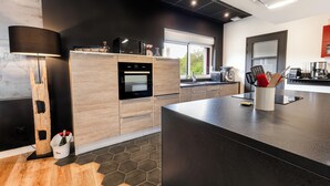 A modern kitchen with a built-in oven, a microwave, and a coffee machine.