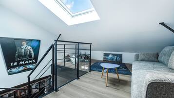 A modern loft with a skylight, a staircase, a sofa, and posters on the walls.