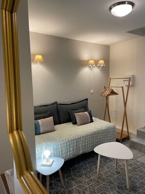 A bedroom with a bed, bedside tables, wall-mounted lamps, a coat rack, and a patterned floor. - Le Marais, rue Volta Studio with A/C (Paris)