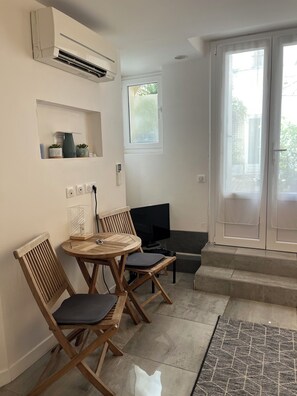 A room with a round wooden table, two chairs, a television, and a window.