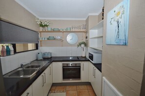 Kitchen equipped with double sink, oven, microwave, and ample storage options.