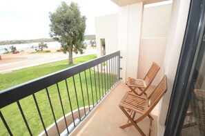Enjoy the serene view from this balcony with a grassy area, tree, and road view.