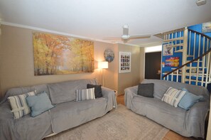 Relax in this inviting living room with two sofas, a statement painting, and a staircase leading to the upper level.
