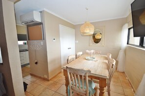 Enjoy meals in this dining area with a table and chairs, a kitchen door, and a hanging light fixture.