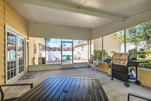 A covered patio with a grill, a table, and chairs.