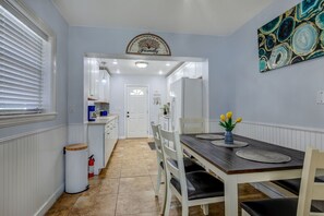 A dining area with a wooden table, white chairs, and a vase of yellow flowers.