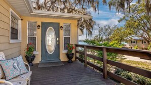 A house with a porch, a wooden deck, and a view of a lake.