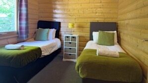 Une cabine équipée de deux lits, d’une table de chevet et d’une fenêtre avec des rideaux.