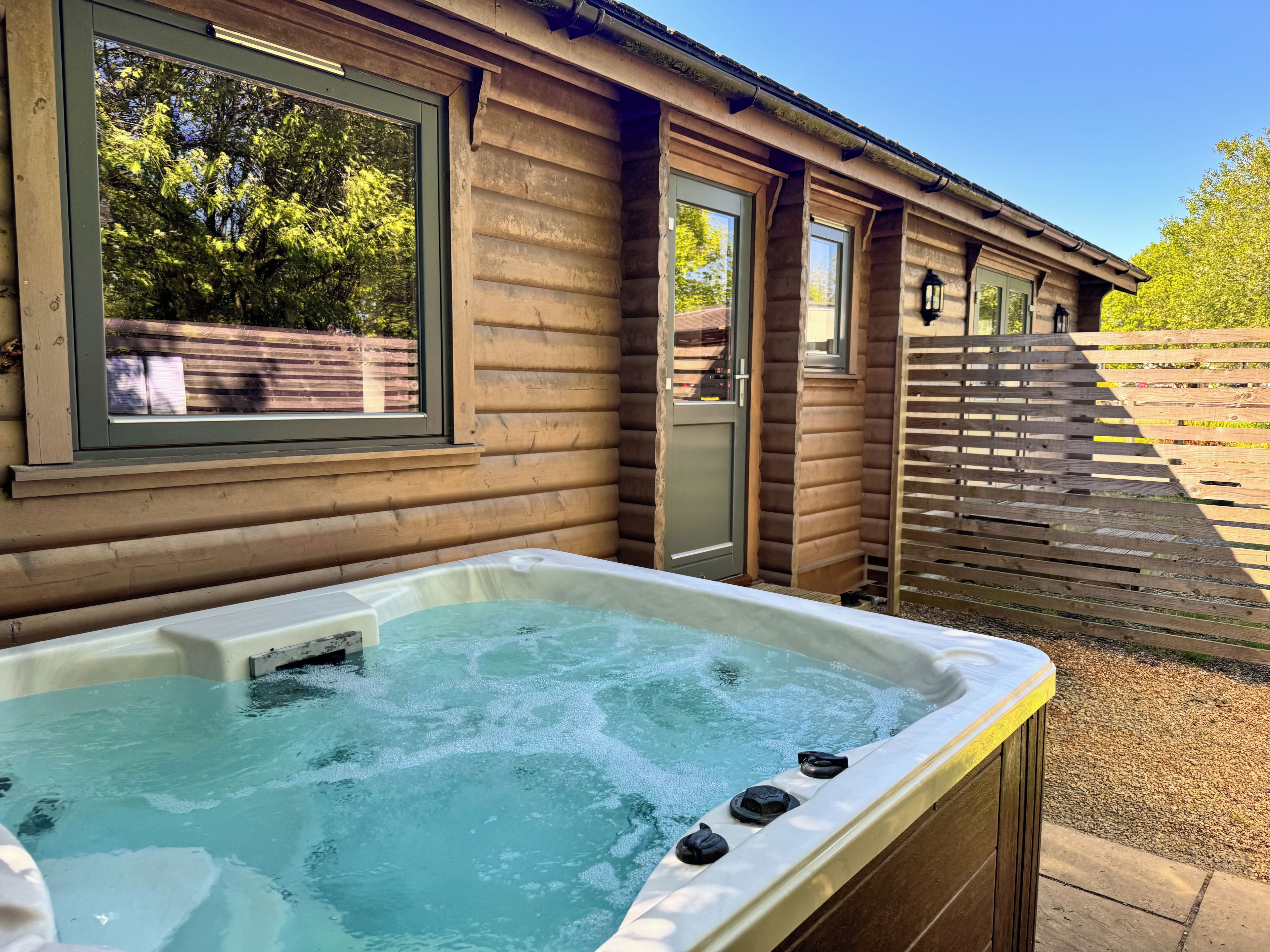 A wooden cabin with a hot tub, a window, and a door.