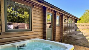 Une cabane en bois avec un jacuzzi, une fenêtre et une porte.