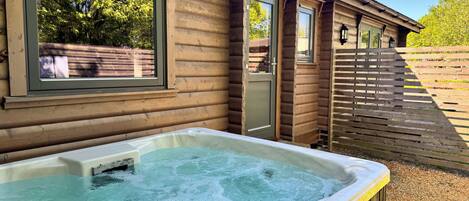 Une cabane en bois avec un jacuzzi, une fenêtre et une porte.
