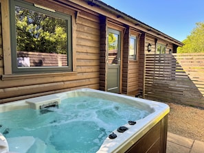 A wooden cabin with a hot tub, a window, and a door. - Chestnut Meadow Cabin (East Sussex)