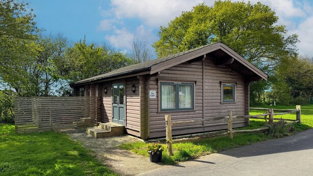Une petite cabane en bois avec une véranda, une porte et une fenêtre.