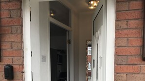 A narrow hallway with a carpeted floor, a white door on the right, and a brick wall on the left. - Modern 3-bed House With Parking Bamber Bridge, Preston (Preston)