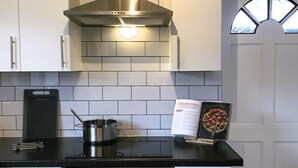 A kitchen with white cabinets, a stainless steel range hood, a black countertop, and a built-in oven. - Modern 3-bed House With Parking Bamber Bridge, Preston (Preston)