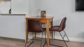 Una cocina moderna con armarios blancos, una mesa de madera, dos sillas de cuero marrón y un recipiente de vidrio sobre la mesa.