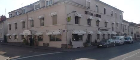 A hotel with multiple balconies, a restaurant, and a parking area.