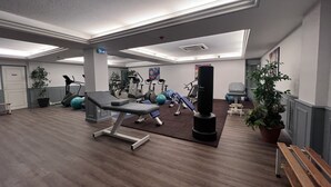A gym with exercise equipment, a punching bag, and potted plants. - Logis Hôtel de la Poste (Vitry-le-Francois)