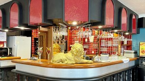 A bar area with a lion statue, red and black decor, and hanging wine glasses. - Logis Hôtel de la Poste (Vitry-le-Francois)