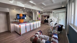 A modern hotel lobby with a reception desk, seating area, and a large window. - Logis Hôtel de la Poste (Vitry-le-Francois)