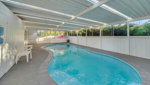 An indoor swimming pool with a curved design, surrounded by a covered patio area with white walls and large windows. - Private House - Pool, Games and Fire Pit Bathurst (Robin Hill)