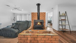 A living room with a brick fireplace, a sofa, and a ladder shelf. - Private House - Pool, Games and Fire Pit Bathurst (Robin Hill)