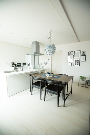 A modern kitchen with a white island, black chairs, and a hanging light fixture.