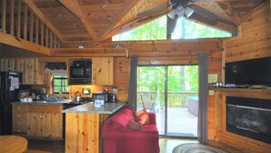 A cabin interior with a kitchen, dining area, and a living room with a fireplace. - Sleepy Creek - Creekside Escape (Berkeley Springs)