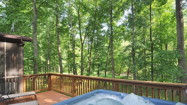 A hot tub on a wooden deck with a view of a forest. - Sleepy Creek - Creekside Escape (Berkeley Springs)