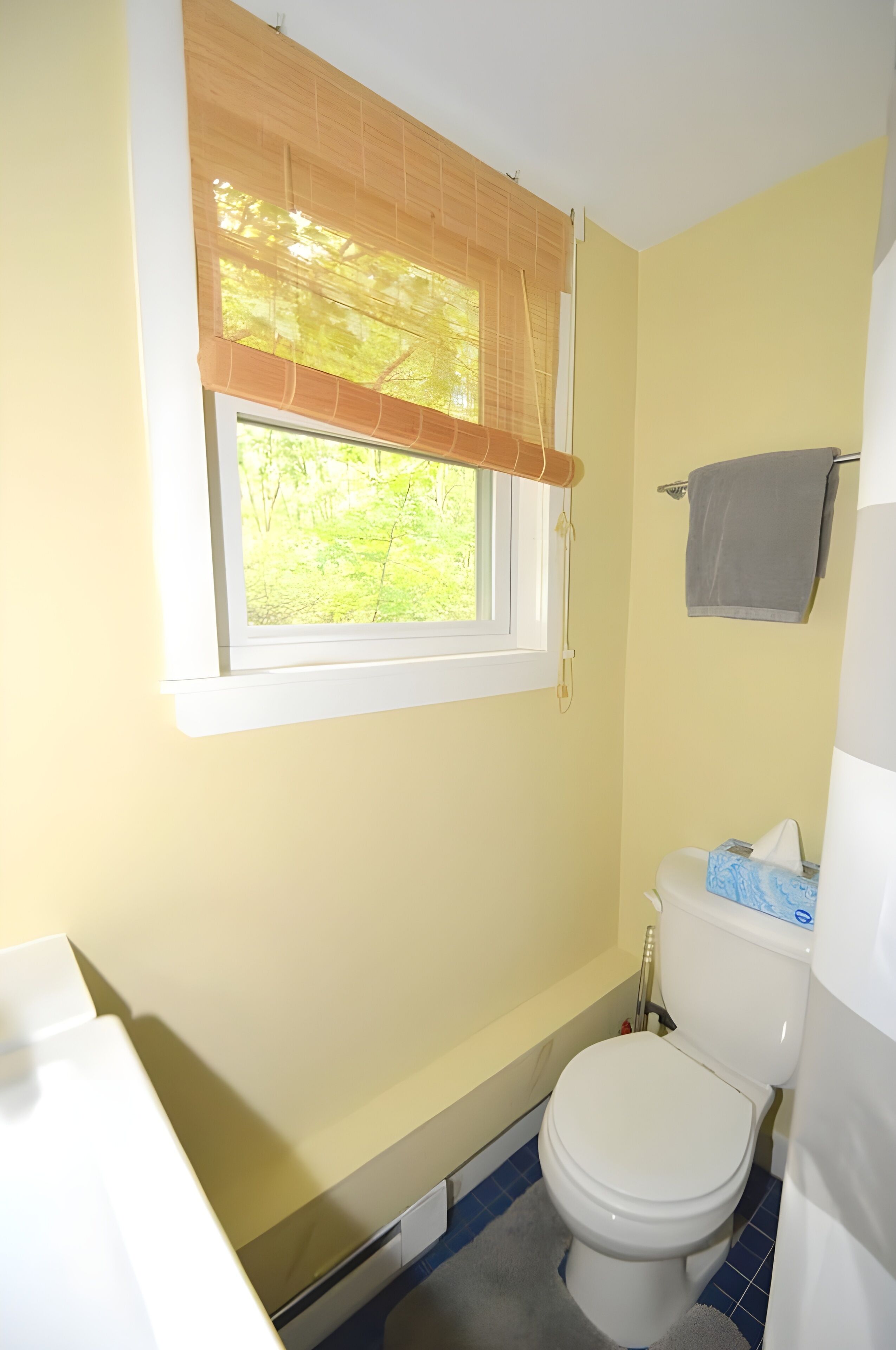 Ein kleines Badezimmer mit Toilette, einem Fenster mit Jalousie und einem Handtuch an einem Halter.