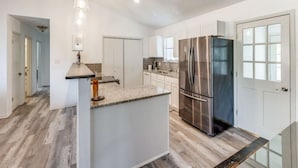 Een moderne keuken met een centraal eiland, roestvrijstalen apparatuur en een licht houten vloer.