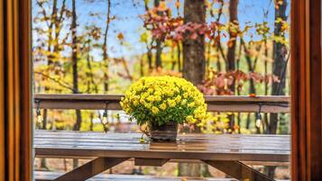 A wooden picnic table with a potted yellow flower arrangement.