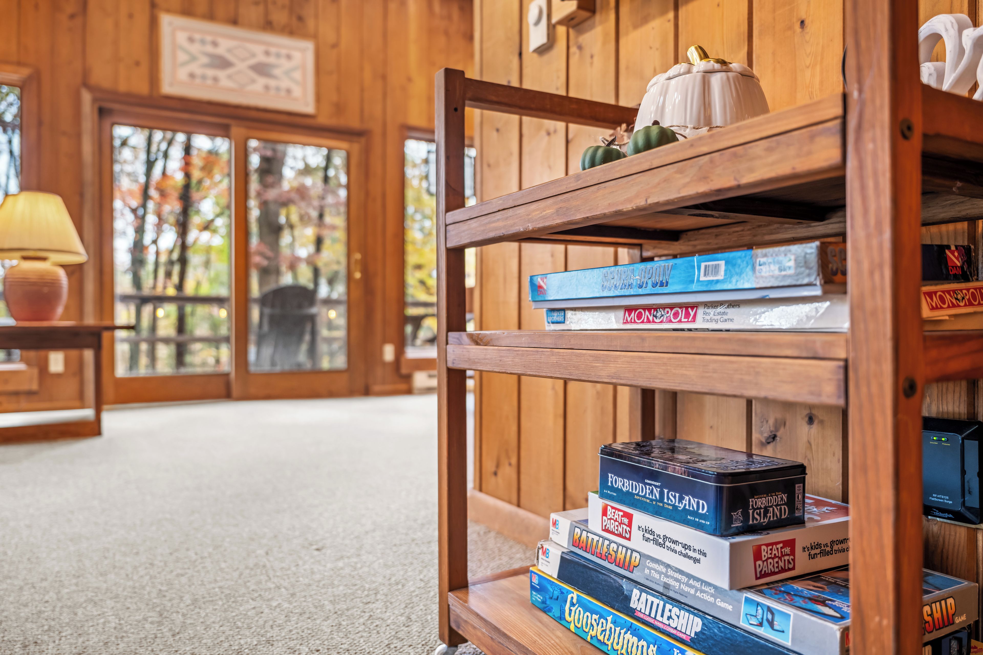 A wooden shelf with board games and a small pumpkin decoration.