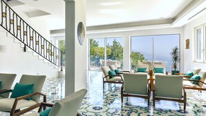 Amplia sala de estar con piscina, ventanas grandes y escalera con barandillas decorativas.