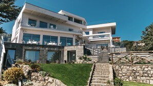 Un edificio moderno de varios pisos con fachada de piedra, amplias ventanas y zonas de estar al aire libre.