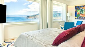 Una habitación de hotel con cama, una silla, un escritorio y vista al mar.