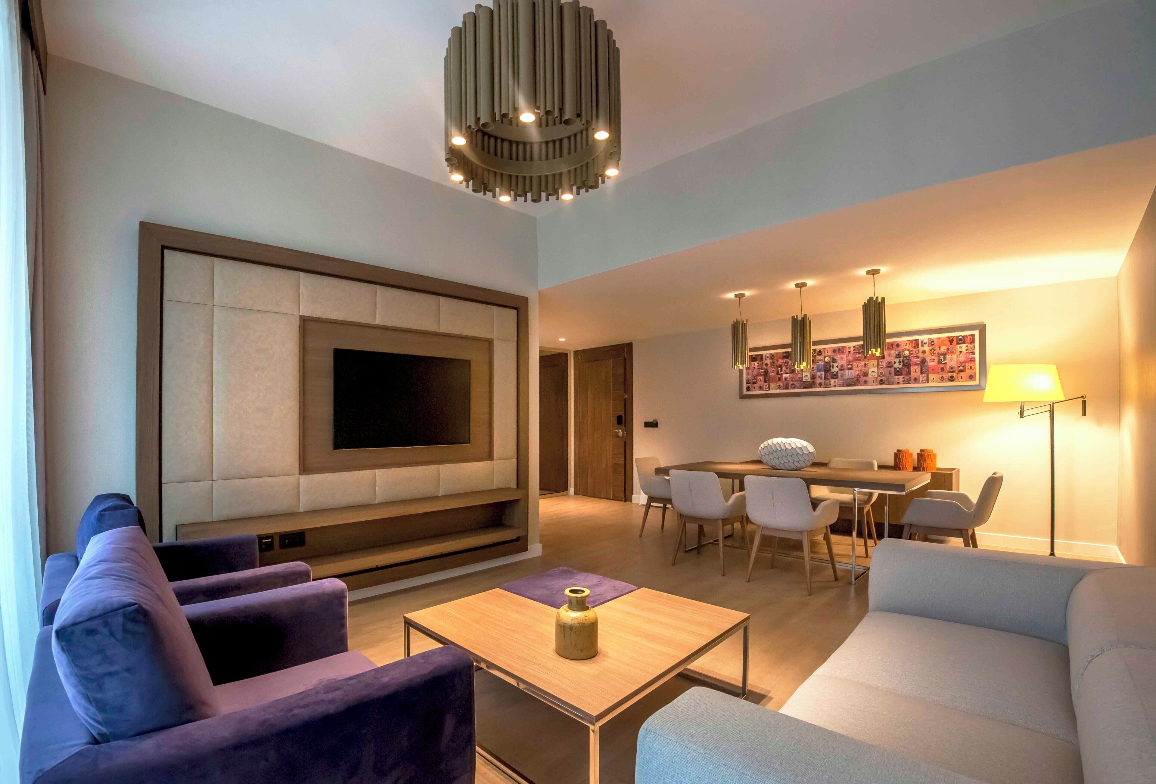 Ein modernes Wohnzimmer mit Flachbildfernseher, Sofas, einem Couchtisch und einem Essbereich mit Stühlen und einem Tisch.
