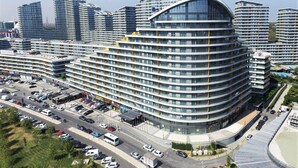 A modern multi-story hotel with a curved facade, multiple balconies, and a parking lot with various vehicles. - The Superior Living Batisehir  (Istanbul)