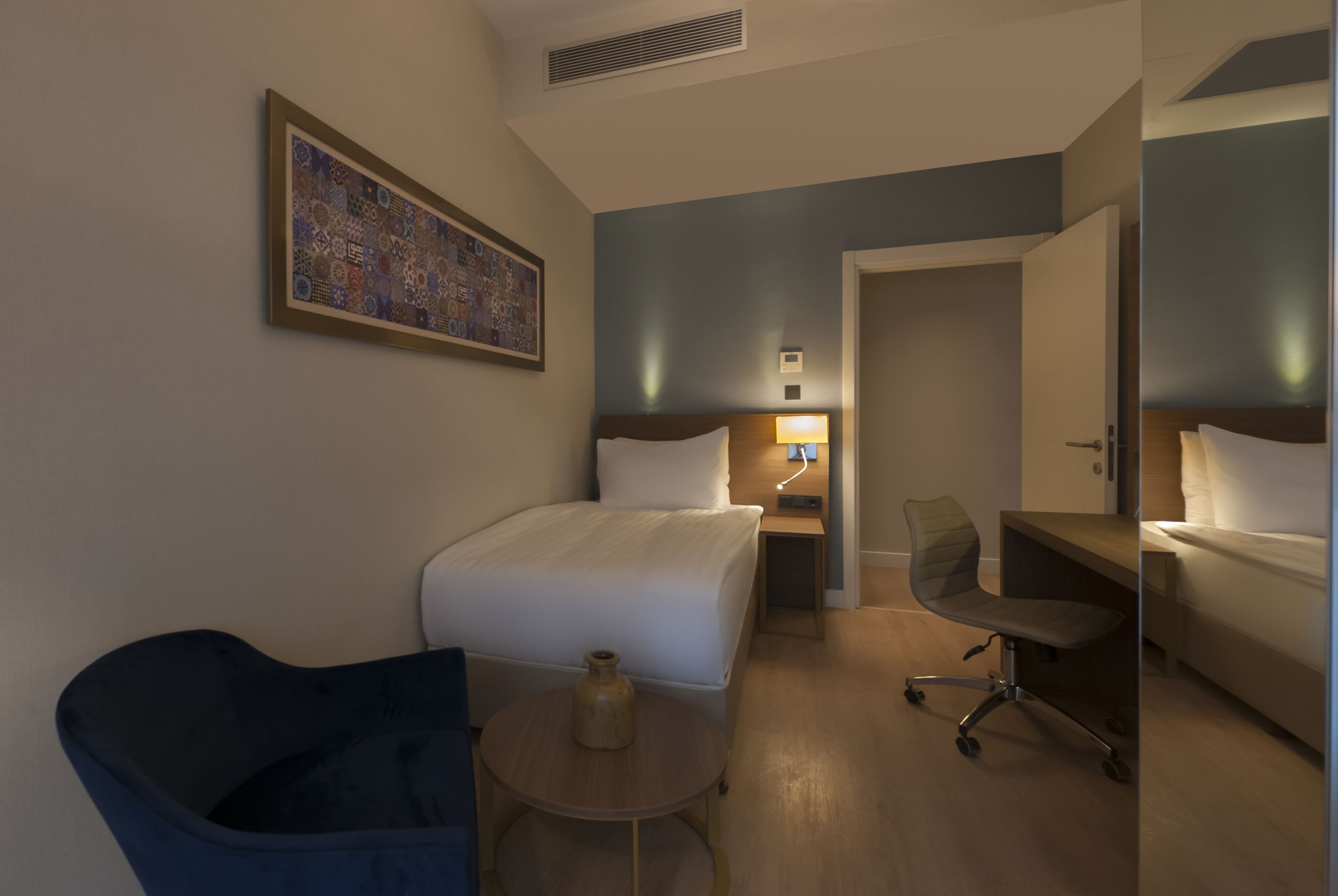 Ein Hotelzimmer mit Bett, Schreibtisch, Stuhl und einem kleinen Tisch.